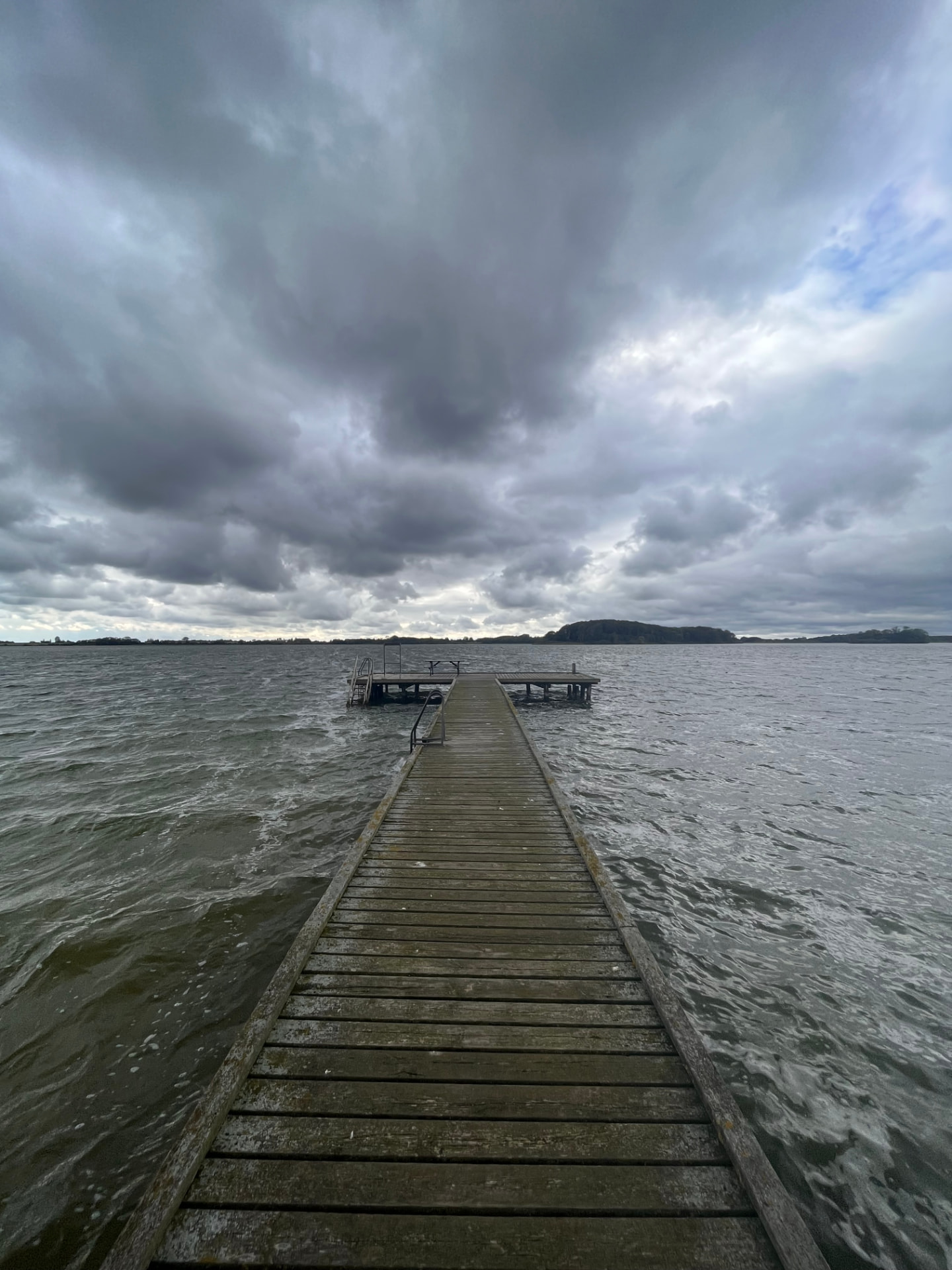 A pier reaching into the sea under storm clouds